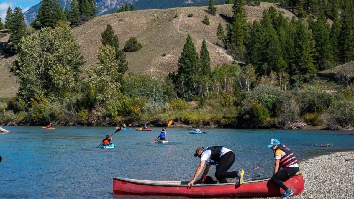 Photo of two people launching canoe into river 