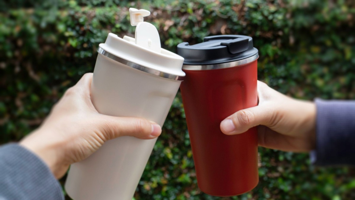 Photo of two reusable coffee mugs 'cheersing'