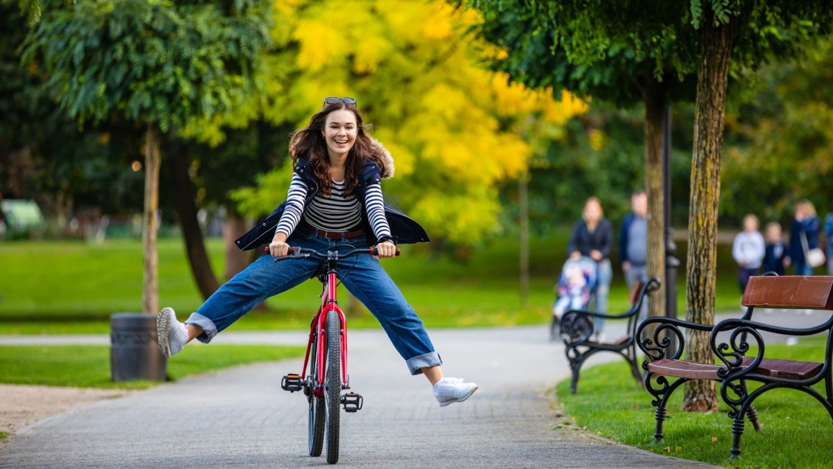 A smiling woman on a with legs outstretched on a bike
