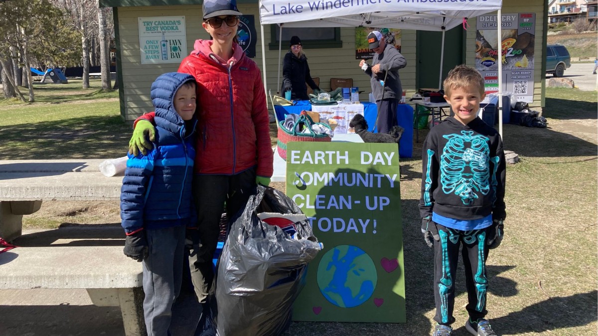 Smiling mother and two children with full garbage bag 