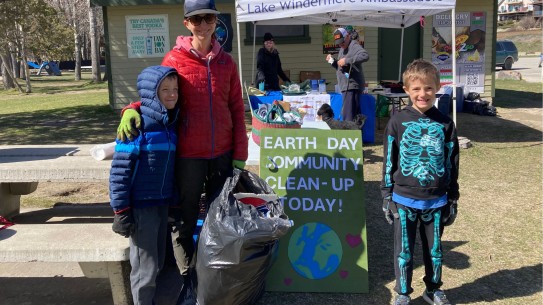 Smiling mother and two children with full garbage bag
