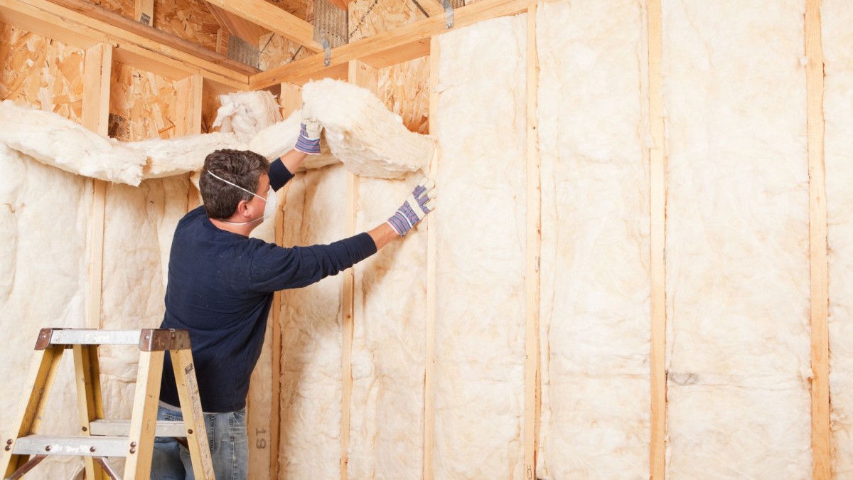 A man installing insulation in a wall