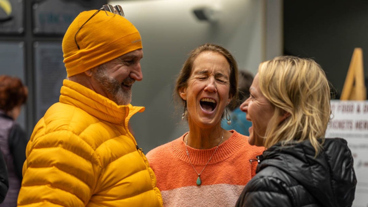 Three laughing people wearing bright coloured jackets