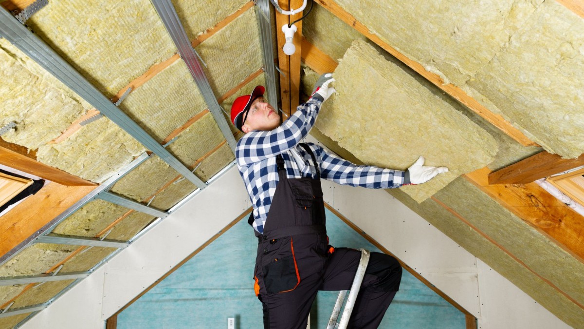 a tradesman installing insulation panels in a ceiling