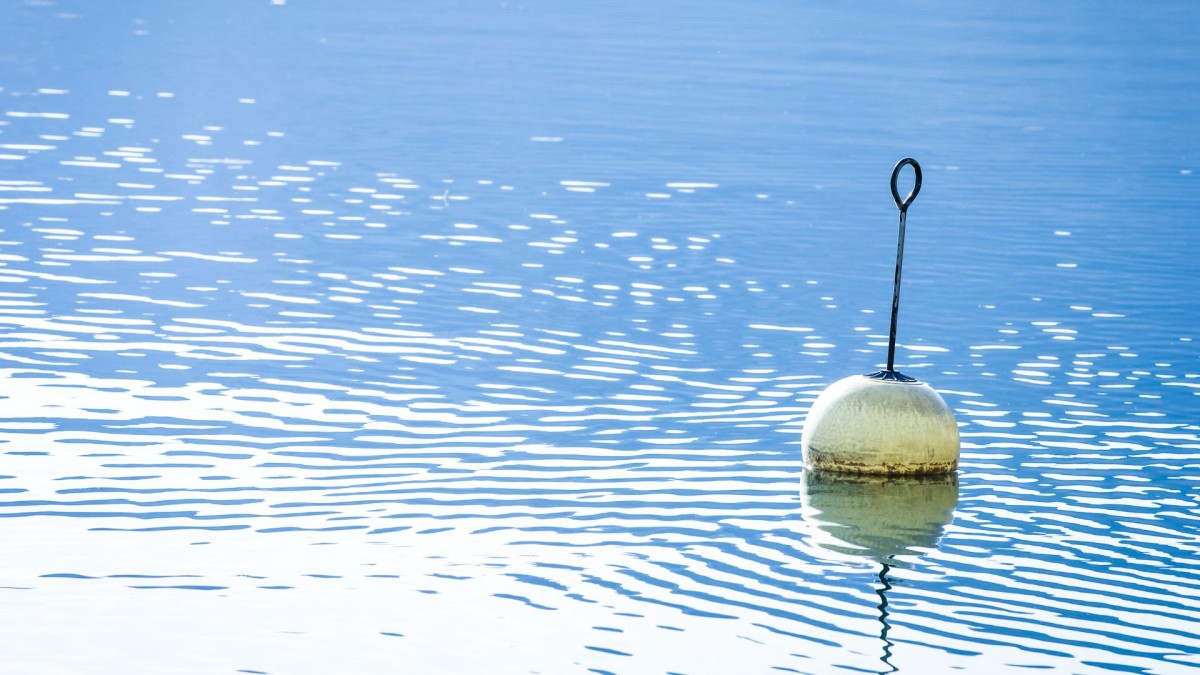 a white buoy reflected on a gently rippled lake surface