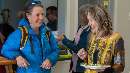 two ladies chatting while serving themselves plates of food